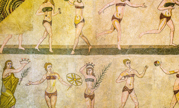 Mosaic depicts women in bikinis engaging in athletic activities like running and exercising, set against a patterned backdrop. They hold objects like balls and branches, symbolizing both recreation and celebration.
