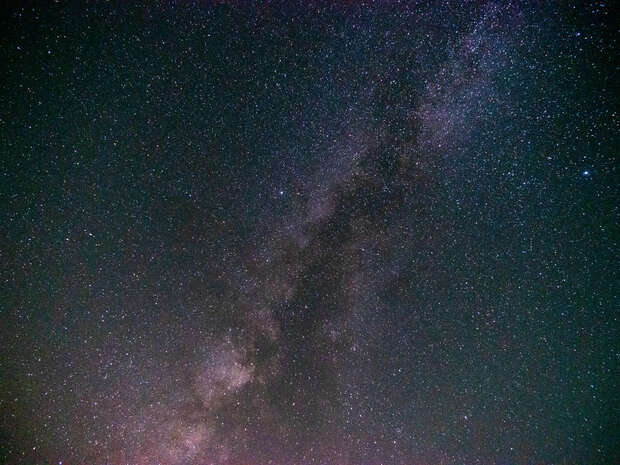A dense cluster of stars forms the Milky Way, stretching diagonally across a dark, star-filled night sky.