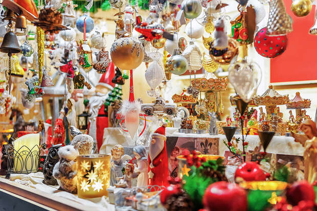Colorful Christmas decorations displayed on a market stall; ornaments and figurines fill the space, creating a festive atmosphere with lights, candles, and holiday-themed items surrounding the scene.