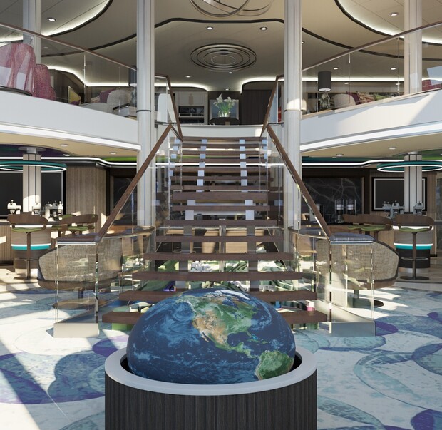 A large, decorative globe is displayed beneath a grand wooden staircase in a modern, well-lit interior with glass railings, seating areas, and circular ceiling lights.