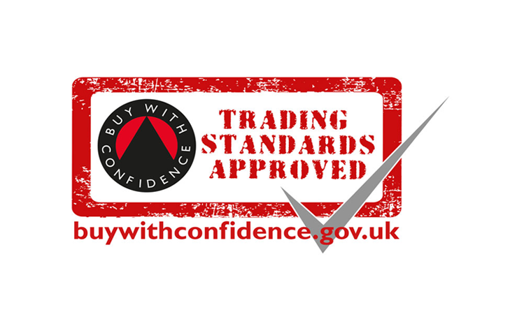 A circular logo reads "BUY WITH CONFIDENCE" featuring a check mark, adjacent to stenciled text: "TRADING STANDARDS APPROVED." Below, "buywithconfidence.gov.uk" is written in red.